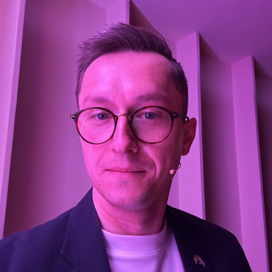 Me, looking into camera, face to one side slightly to show a thin microphone on my left cheek.